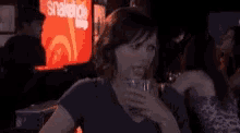 a woman is sitting at a table drinking a glass of beer in a bar .