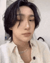 a close up of a person wearing a white shirt and a pearl necklace .