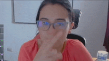 a woman wearing glasses is making a funny face while sitting in front of a computer .