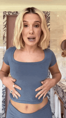 a woman in a blue shirt is holding her stomach
