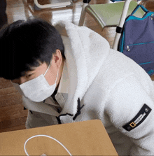 a man wearing a national geographic jacket laying on the floor