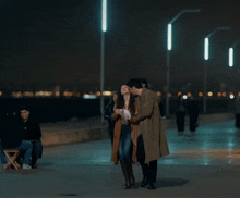 a man and a woman are kissing on a sidewalk in the dark