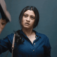 a woman in a blue shirt is making a funny face with her mouth open