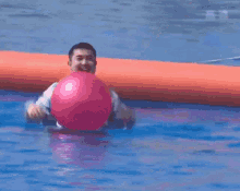 a man is holding a pink ball in a pool with chinese writing