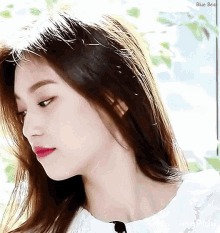 a close up of a woman 's face with long hair and a white shirt .