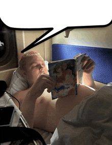 a shirtless man is reading a book with a picture of a girl on the cover