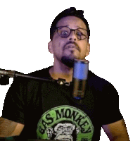 a man wearing glasses and a gas monkey shirt is talking into a microphone .