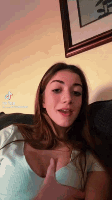 a young woman is sitting on a couch giving a thumbs up .