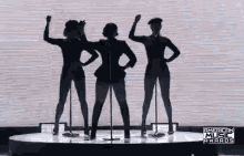 a group of women are dancing on a stage in front of microphones .