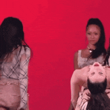 three women are dancing in front of a red background .
