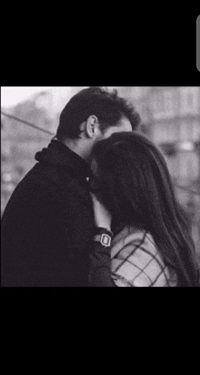 a black and white photo of a man and a woman hugging each other .