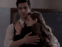 a man in a suit and tie is hugging a woman in a black shirt