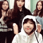 a girl wearing a hooded sweatshirt is surrounded by other girls