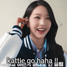 a girl in a varsity jacket is smiling and talking on a cell phone