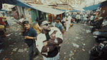 a man wearing sunglasses stands in a crowded street surrounded by other people