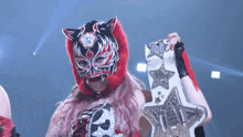 a woman in a cat mask is holding a wrestling belt