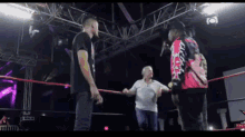a man in a red jacket with the word miami on it is standing in a wrestling ring