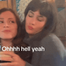two women are sitting next to each other with the words ohhhh hell yeah written on the bottom