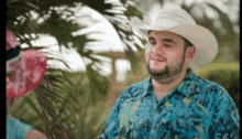 a man wearing a cowboy hat and a blue shirt is smiling
