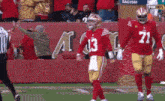 a football player with the number 13 on his jersey stands on the field
