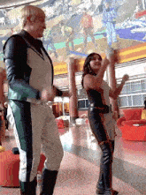 a man and woman are dancing in front of a mural
