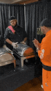 a man in an orange sweatshirt is standing next to a man in a chef hat