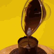 chocolate is being poured into a cup on a yellow surface