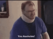 a man wearing a neck brace and a blue shirt says " you assholes "