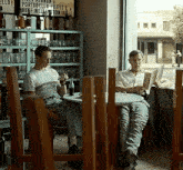 two men sit at a table in front of a sign that says portobello fillets and beef wellington
