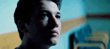 a close up of a man 's face in a dark room with a yellow stripe on the wall .