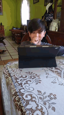 a young boy is sitting at a table with a tablet on it