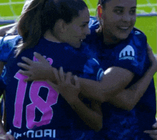 a female soccer player wearing the number 18 hugging another player