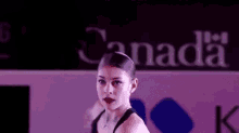 a woman is dancing in front of a sign that says canada