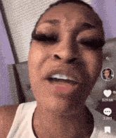 a woman with braces on her teeth is making a funny face while wearing a white tank top .