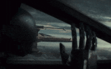 a man looks out a window at a fighter jet