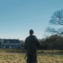 a man standing in a field looking at a building