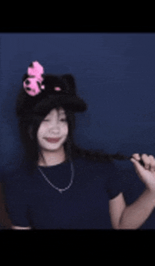a girl wearing a black cat hat with a pink flower on it .