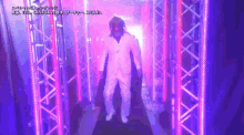 a man in a white suit is walking through a tunnel with pink lights