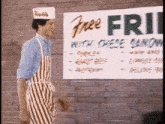 a man in an apron is standing in front of a sign that says free fries