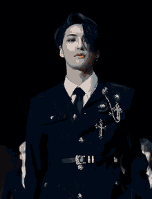 a young man wearing a black suit and tie with a cross on his chest .