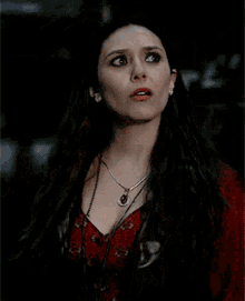 a woman wearing a red top and a necklace with a red pendant