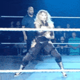 a woman is standing in a wrestling ring with a referee in the background