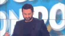 a man with a beard is dancing on a stage in front of a sign that says ' o ' on it .