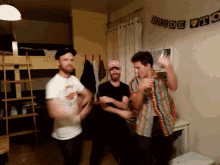 three men are dancing in a room with a bride to be banner hanging on the wall