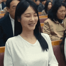 a woman in a white shirt is smiling while sitting in a church