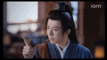 a young man in a traditional costume is pointing his finger up .