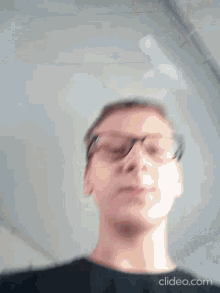 a blurry photo of a man wearing glasses and a black shirt .
