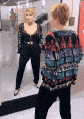 a woman in a sequined jacket stands in front of a mirror in front of a sign that says ' the ' on it