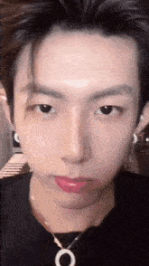 a close up of a young man 's face wearing a necklace and earrings .