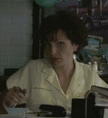 a woman in a yellow shirt sits at a desk with a stapler on it